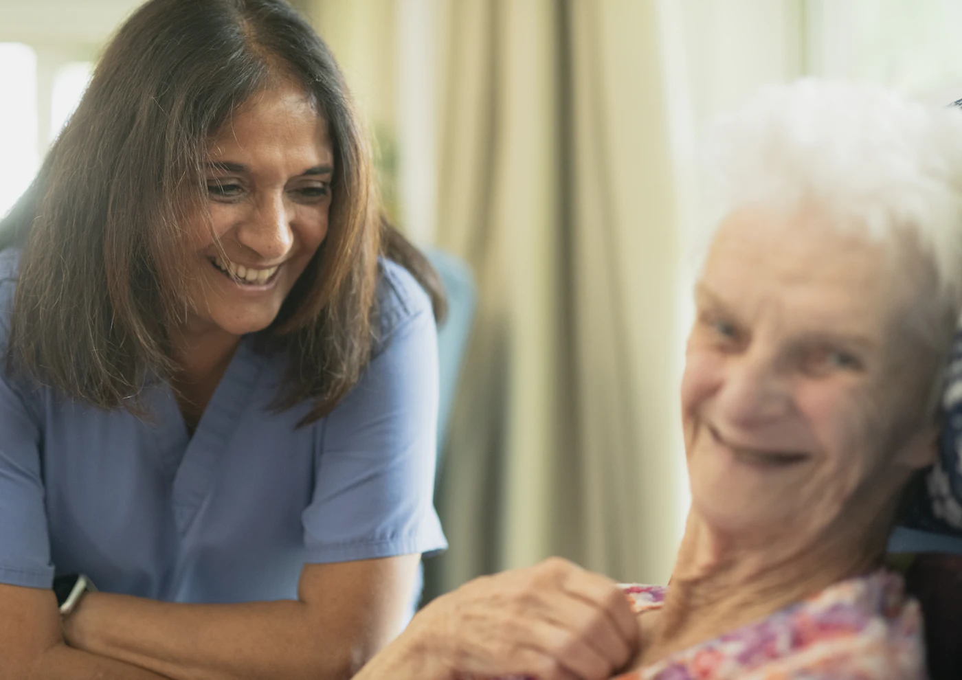 A carer smiling warmly with an older woman