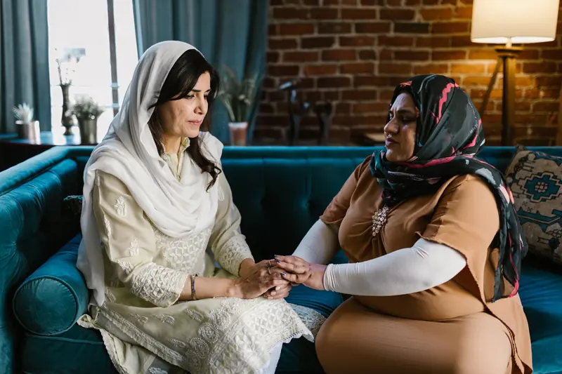 Two women holding hands in conversation on a sofa